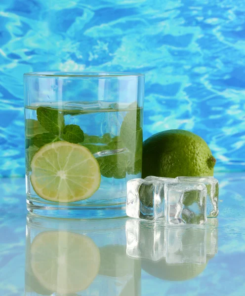 Glass of water with ice, mint and lime on sea background — Stock Photo, Image