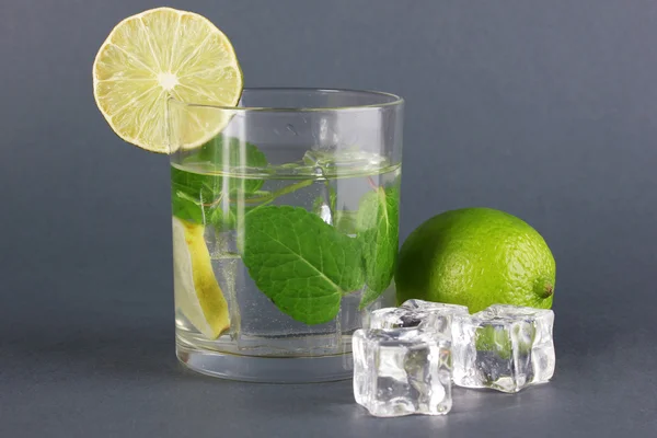 Verre d'eau avec glace, menthe et chaux sur fond gris — Photo