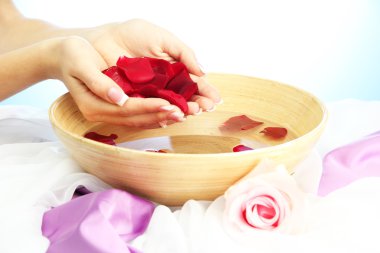 kadın eliyle su yaprakları, mavi zemin üzerine ahşap kase