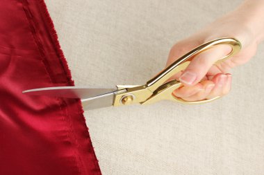 bej kumaş arka plan üzerinde kırmızı kumaş kesmek bir terzi