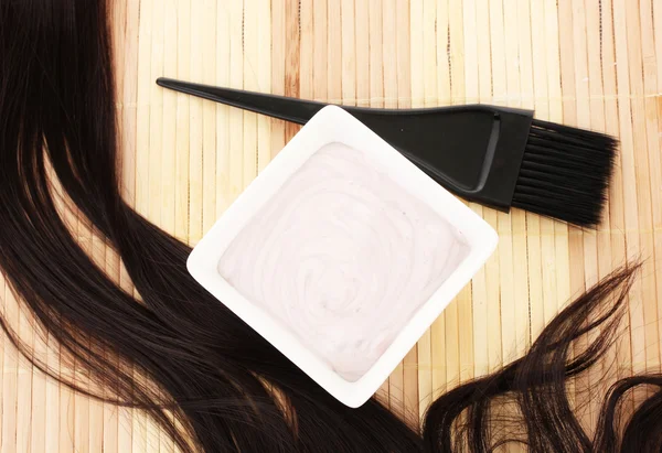 Фарба для волосся в мисці і пензлик для фарбування волосся на бежевому бамбуковому килимку, крупним планом — стокове фото