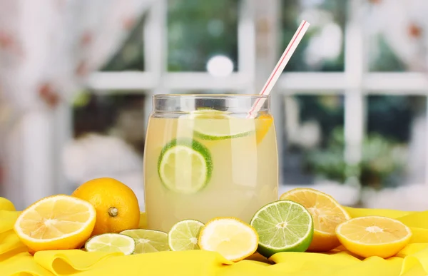 Citrus lemonade in glass bank of citrus around on yellow fabric on window background — Stock Photo, Image
