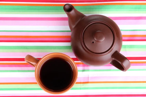 Draufsicht auf Tasse Tee und Teekanne auf bunten Tischdecken — Stockfoto