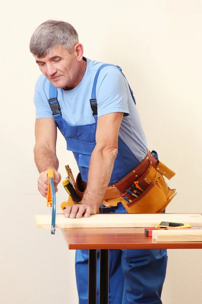 Construtor de tábuas de serra na mesa no fundo da parede — Fotografia de Stock