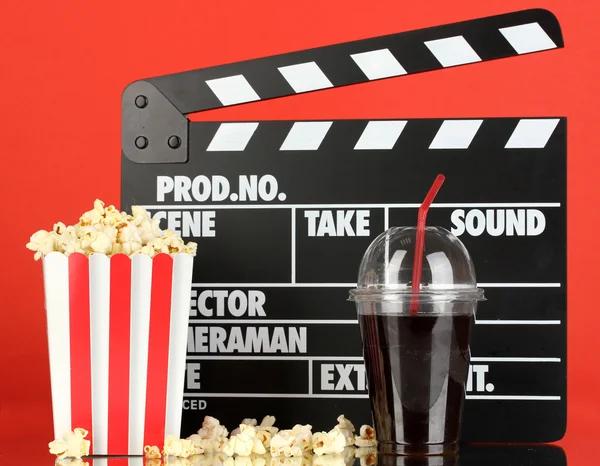 Film Filmklapper, cola en popcorn op rode achtergrond — Stockfoto