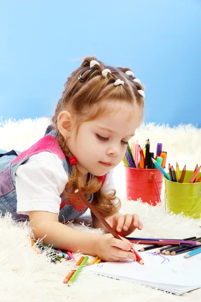 Mignonne petite fille jouant avec des crayons multicolores, sur fond bleu — Photo