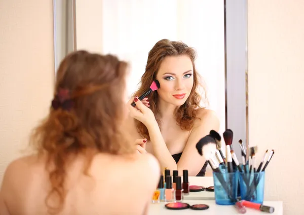 Młoda piękna kobieta robi makijaż w pobliżu lustra — Zdjęcie stockowe