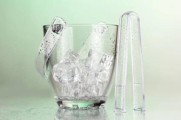 Glass ice bucket on light green background — Stock Photo, Image