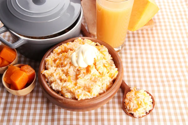 Assaggia il porridge di riso con zucca e bicchiere di succo su fondo tovaglia — Foto Stock