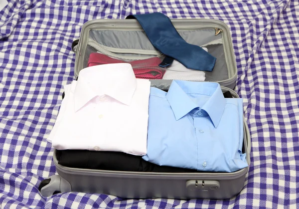 Відкрита сіра валіза з одягом на простий — стокове фото