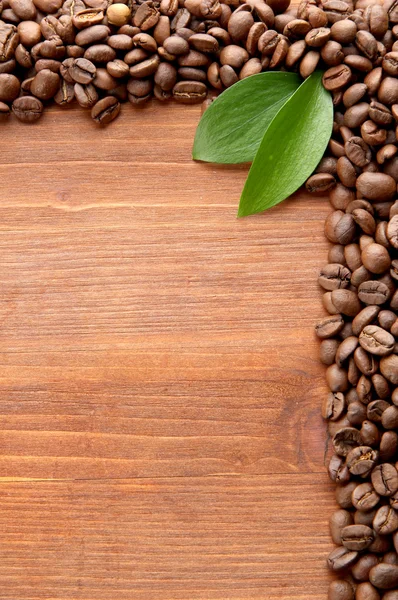 Kahve çekirdekleri ile ahşap arka plan yapraklarda — Stok fotoğraf