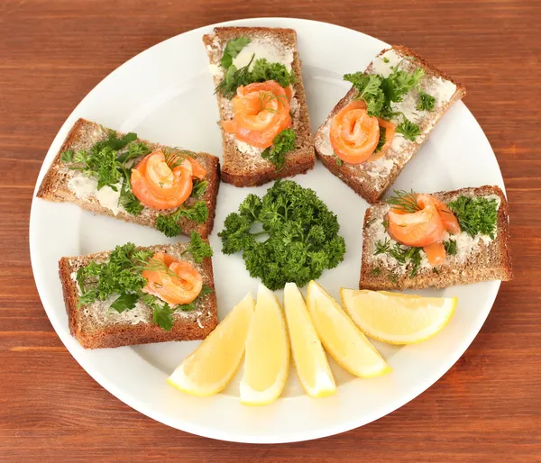 Sandwich au saumon sur assiette, sur fond de bois — Photo