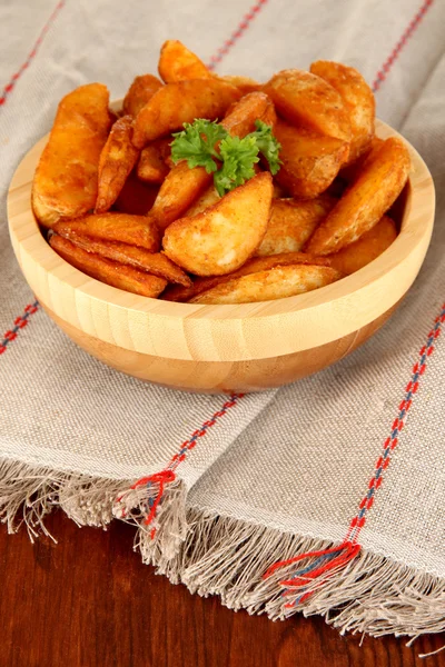 Аппетитная деревенская картошка в миске на деревянном столе крупным планом — стоковое фото