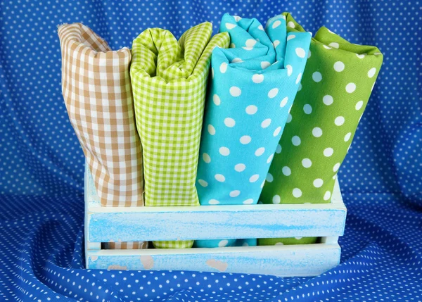 Color mottled fabrics in basket on blue fabric background — Stock Photo, Image