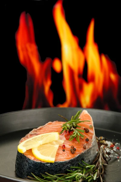 Verse zalm steak op pan, op brand achtergrond, close-up Stockfoto