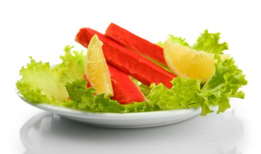 Yengeç sopalarla marul yaprakları ve plaka üzerinde beyaz izole limon