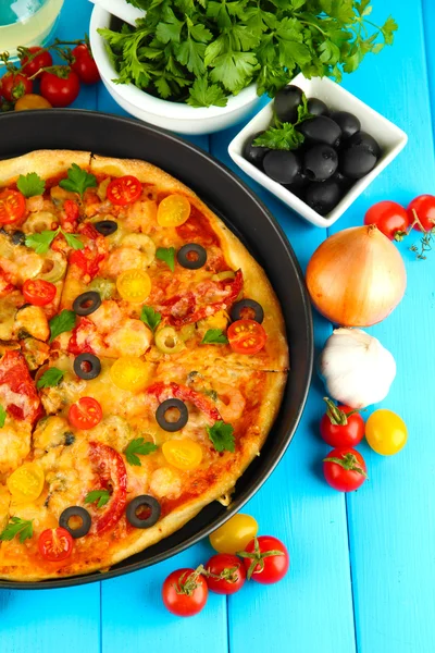 おいしいピザ、野菜、スパイスを木製の青い背景のクローズ アップのカラフルな組成 — ストック写真
