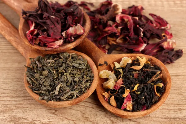 Assortment of dry tea in spoons, on wooden background — Stock Photo, Image