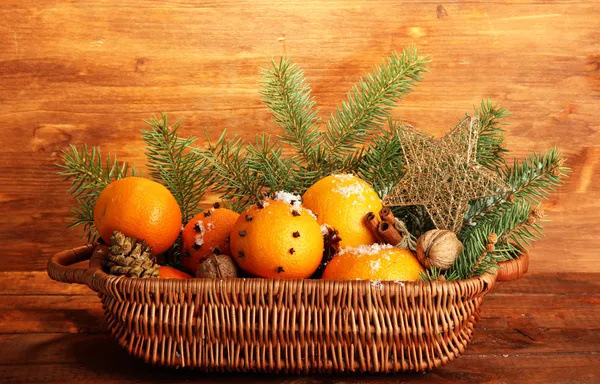 Composição de natal em cesta com laranjas e abeto, sobre fundo de madeira — Fotografia de Stock