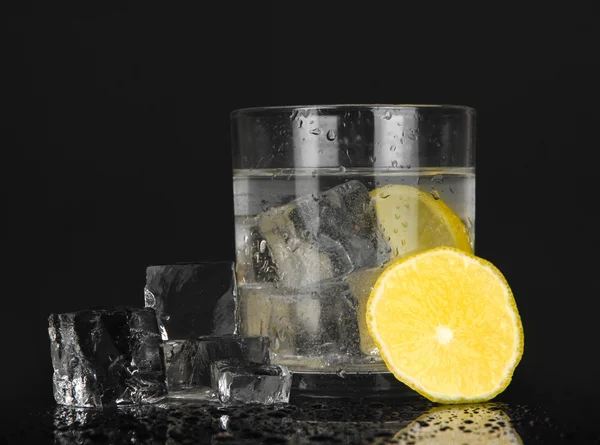 Cubos de hielo en vidrio con limón aislado en negro — Foto de Stock