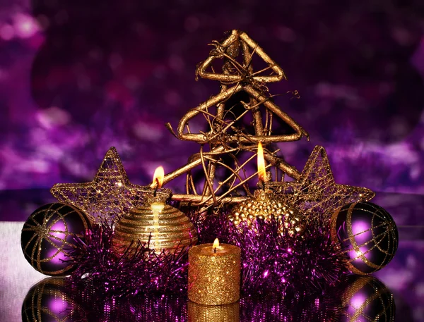 Новорічна композиція зі свічками та прикрасами в фіолетовому та золотому кольорах на яскравому фоні — стокове фото
