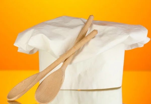 Chef's hat with spoons on orange background — Stock Photo, Image