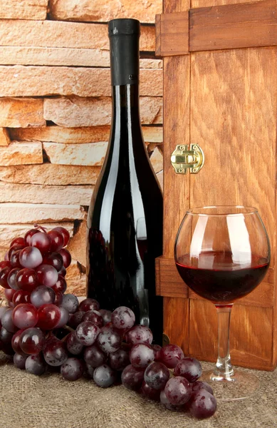 Composition of wine,box and grapes on table on brick wall background — Stock Photo, Image