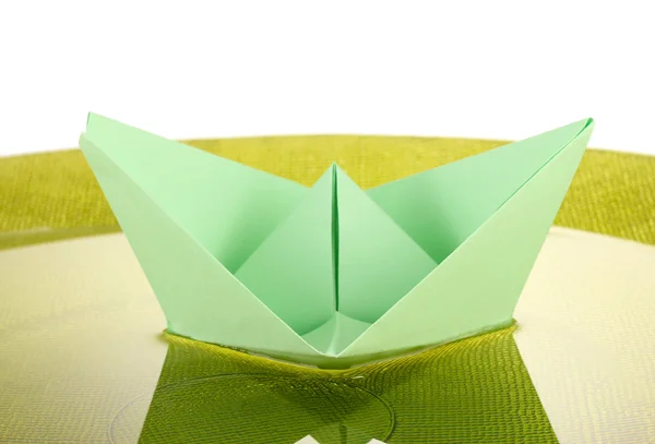 Цветная бумага корабль в воде на зеленой пластине, крупным планом — стоковое фото