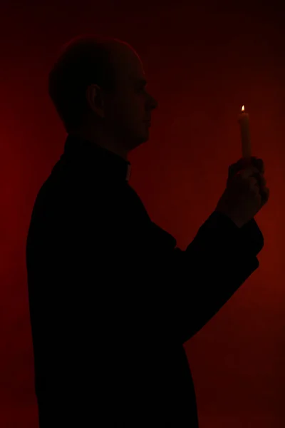 年轻牧师在他的手，孤立在黑色持蜡烛的肖像 — 图库照片