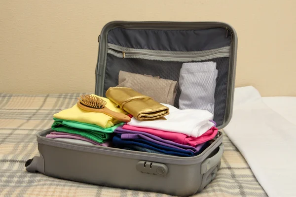Offener grauer Koffer mit Kleidung auf dem Bett — Stockfoto