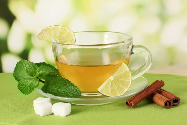 Xícara de chá com hortelã, limão e canela na mesa em fundo brilhante — Fotografia de Stock