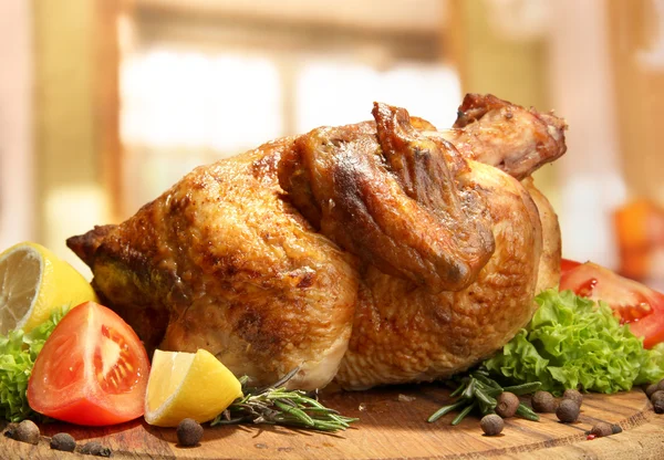 Whole roasted chicken with vegetables on plate, on wooden table in cafe — Stock Photo, Image