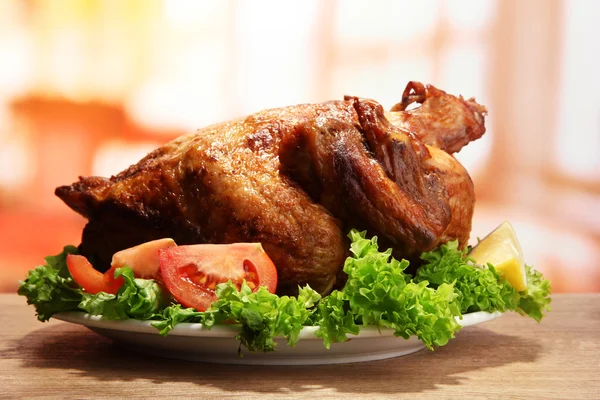 Pollo asado entero con verduras en plato, sobre mesa de madera en cafetería —  Fotos de Stock