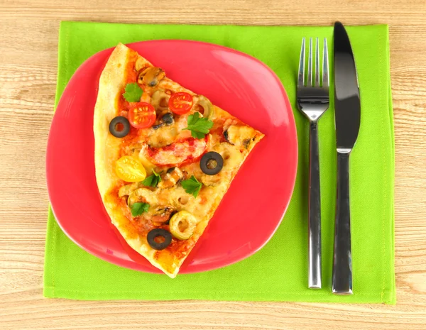 Plate with a slice of delicious pizza on wooden background Stock Picture