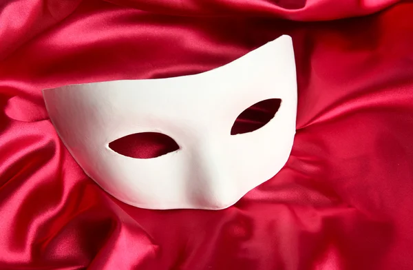 White mask, on red silk fabric — Stock Photo, Image