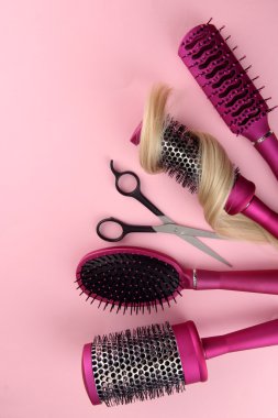 Fırçalar, pembe bir arka plan üzerinde kesme makası ve saç tarağı