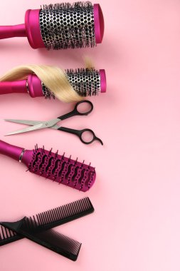 Fırçalar, pembe bir arka plan üzerinde kesme makası ve saç tarağı