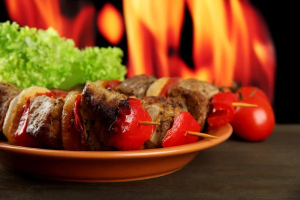 Sabrosa carne a la parrilla y verduras en el plato, sobre fondo de fuego — Foto de Stock