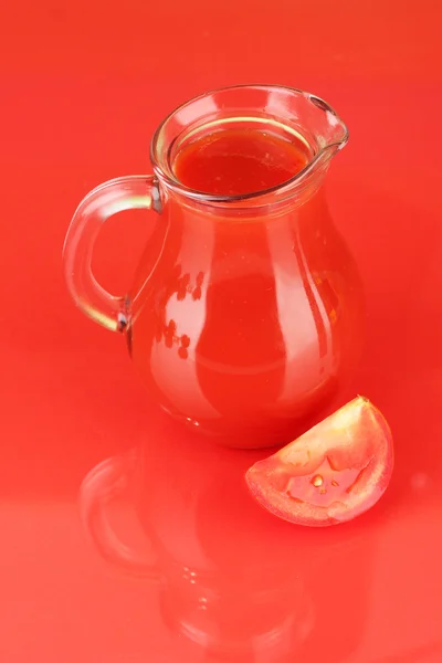 Pleine cruche de jus de tomate, sur fond de couleur — Photo