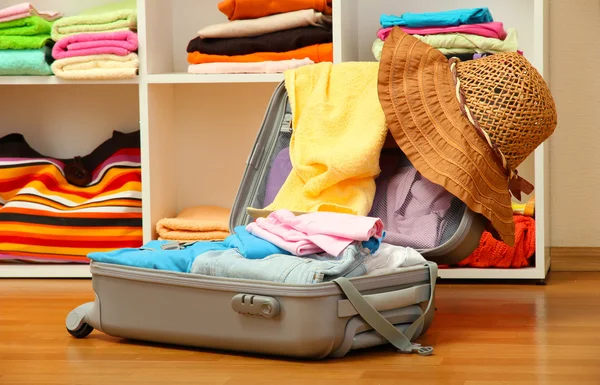 Open silver suitcase with clothing in room — Stock Photo, Image