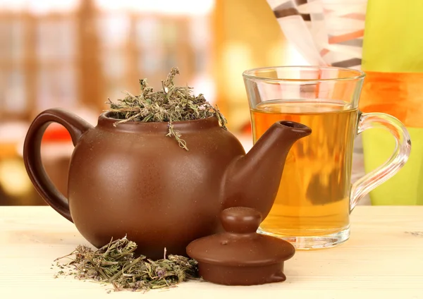 Dried herbs in teapot on wooden table, on bright background. Conceptual photo of herbal tea. — Stock Photo, Image