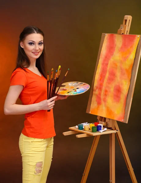Mooie jonge vrouw schilder op het werk, op felle kleur achtergrond — Stockfoto
