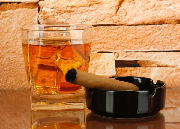 Glass of whiskey and cigar on brick wall background — Stock Photo, Image