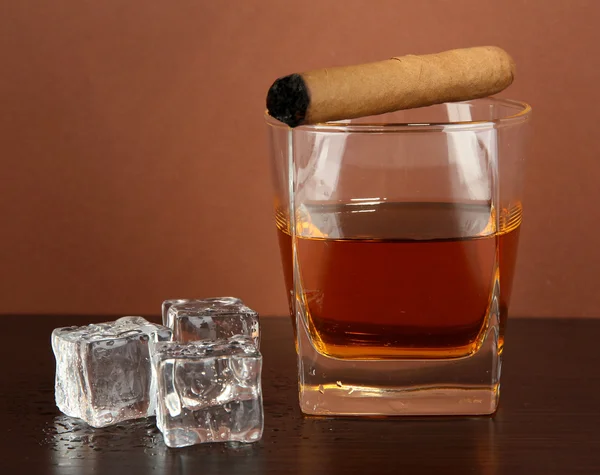 Glass of whiskey and cigar on brown background — Stock Photo, Image
