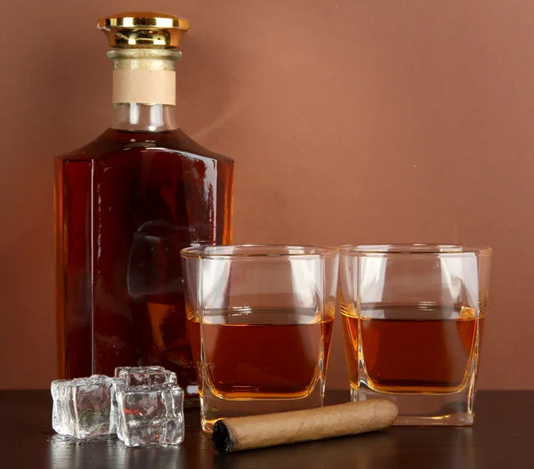 Bottiglia e bicchieri di whisky e ghiaccio su sfondo marrone — Foto Stock