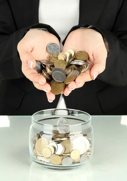 Saving, female hands putting coins into glass bottle, isolated on white — Stock Photo, Image