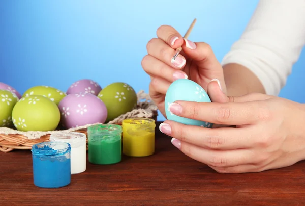 Jovem mulher pintando ovos de Páscoa, no fundo de cor — Fotografia de Stock