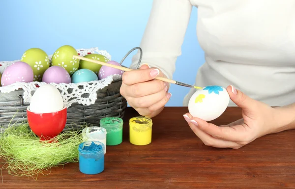 Jovem mulher pintando ovos de Páscoa, no fundo de cor — Fotografia de Stock
