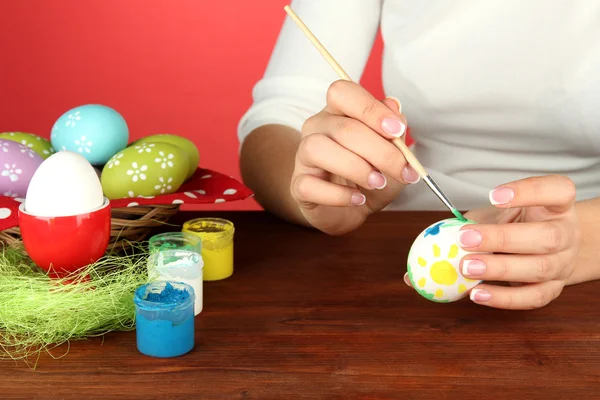 Young woman painting Easter eggs, on color background — Stock Photo, Image