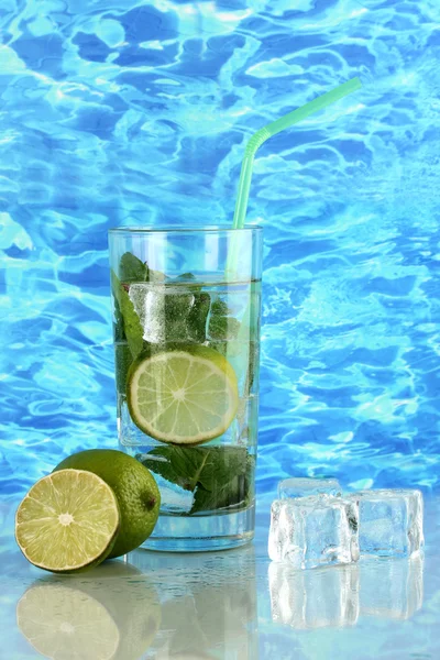 Glass of water with ice, mint and lime on sea background — Stock Photo, Image